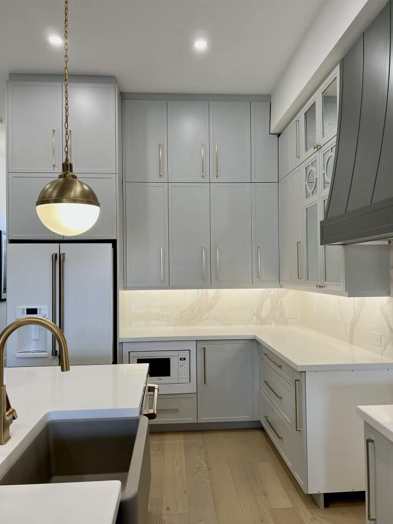 Two-toned grey kitchen gold hardware custom range hood white appliances